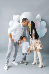 A young stylish family waiting for their second child is kissing against the background 