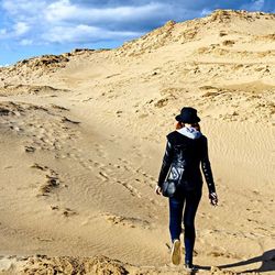 Full length rear view of woman walking on desert
