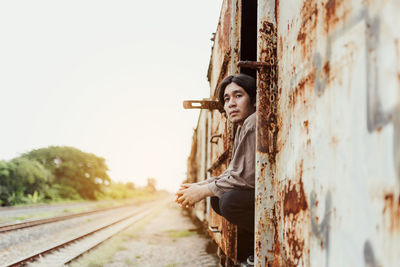 Portrait of smiling handsome asian man standing at public train station. young man standing in old 