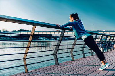 Woman standing on railing against sea