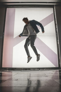Side view of young man jumping on floor