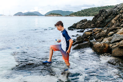 Full length of boy on rock at beach