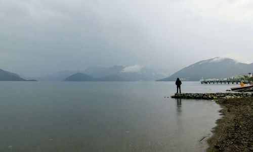 Man standing on mountain by sea against sky