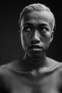 Close-up of shirtless woman against black background