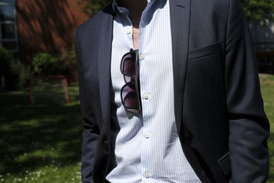 Man in suit with a pair of sunglasses tucked in his shirt