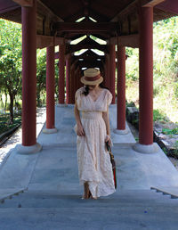 Portrait of young woman standing against trees