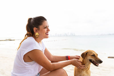 Side view of young woman sitting on beach