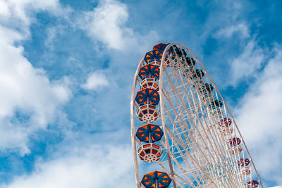 Low angle view of ferris wheel against cloudy sky