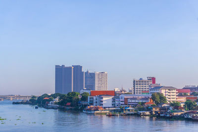 Buildings by sea against clear sky