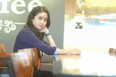 Portrait of young woman sitting on table