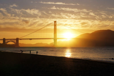 View of suspension bridge over sea during sunset