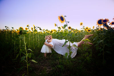 Young woman in sunflower field against sky