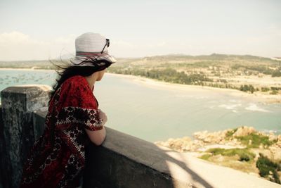 Woman standing by sea against sky