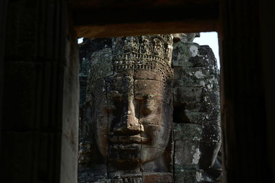 Buddha carving on bayon temple seen through window