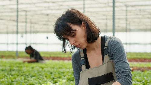 Side view of young woman looking away while standing on field