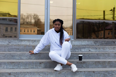 Full length of woman sitting on steps outdoors