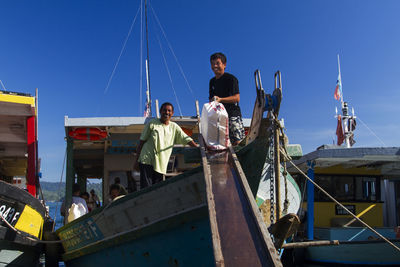 People standing on boat against clear blue sky