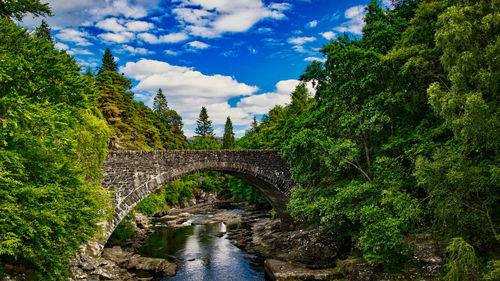 Arch bridge over river against sky