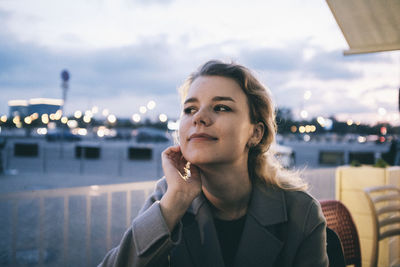 Portrait of young woman looking away in city