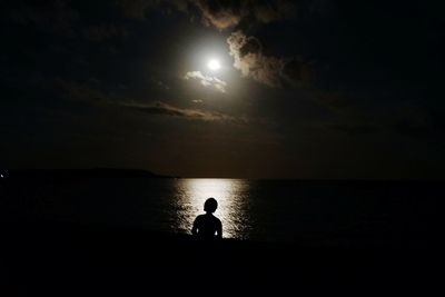 Silhouette of man at beach against sky at sunset