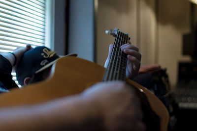 Midsection of man playing guitar while sitting at home