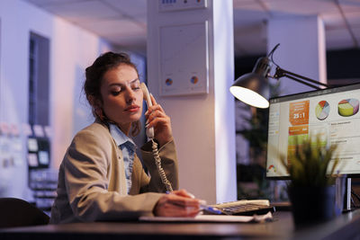 Young woman using mobile phone while sitting on table