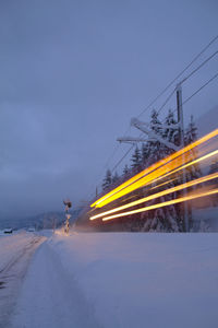 Light trails on road against sky during winter