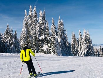 Rear view of man skiing on snow covered mountain against sky