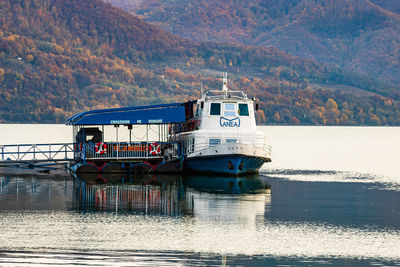 Ship sailing in sea against mountains