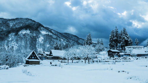 House on snow covered landscape against sky