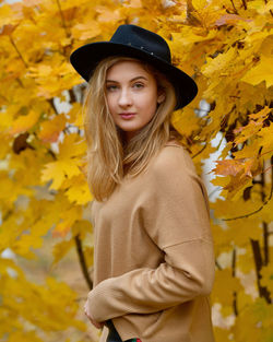 Portrait of beautiful woman standing against yellow during autumn