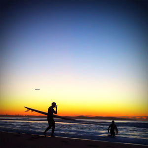 Silhouette of people on beach at sunset