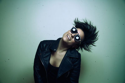 Portrait of young woman standing against wall