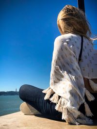 Rear view of woman looking at sea against blue sky