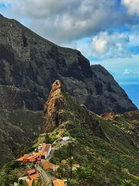 Scenic view of mountain by buildings against sky