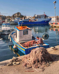 Boats moored at harbor against sky