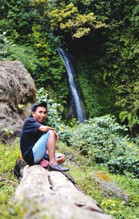 Young man sitting on rock in forest