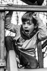 Portrait of boy sitting on railing