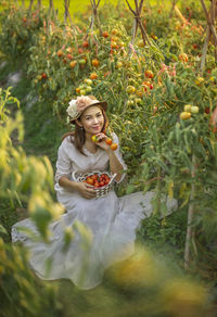 Portrait of woman picking tomatoes in farm