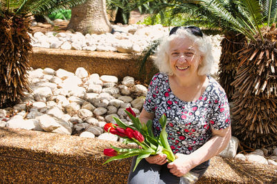 Happy elderly woman with a bouquet of red tulips.