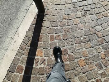 Low section of man standing on cobblestone street