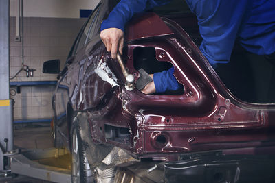 Midsection of mechanic repairing car in garage