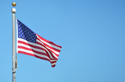 Low angle view of american flag against clear blue sky