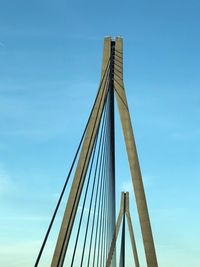 Low angle view of suspension bridge against blue sky