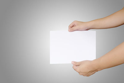 Midsection of woman holding paper against white background