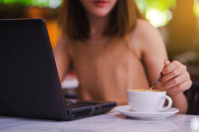 Midsection of woman holding coffee cup on table