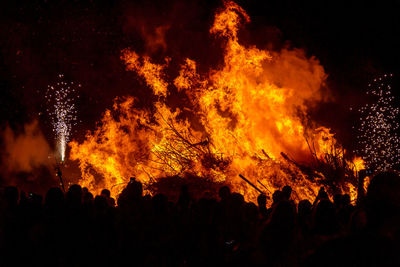 People watching big bonfire. yellow flames rising. night of san juan, fireworks and hot fire.