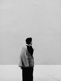 Rear view of woman standing against wall