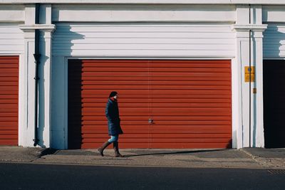 Full length side view of woman walking on footpath against building