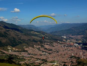 Person doing paragliding over mountain against sky